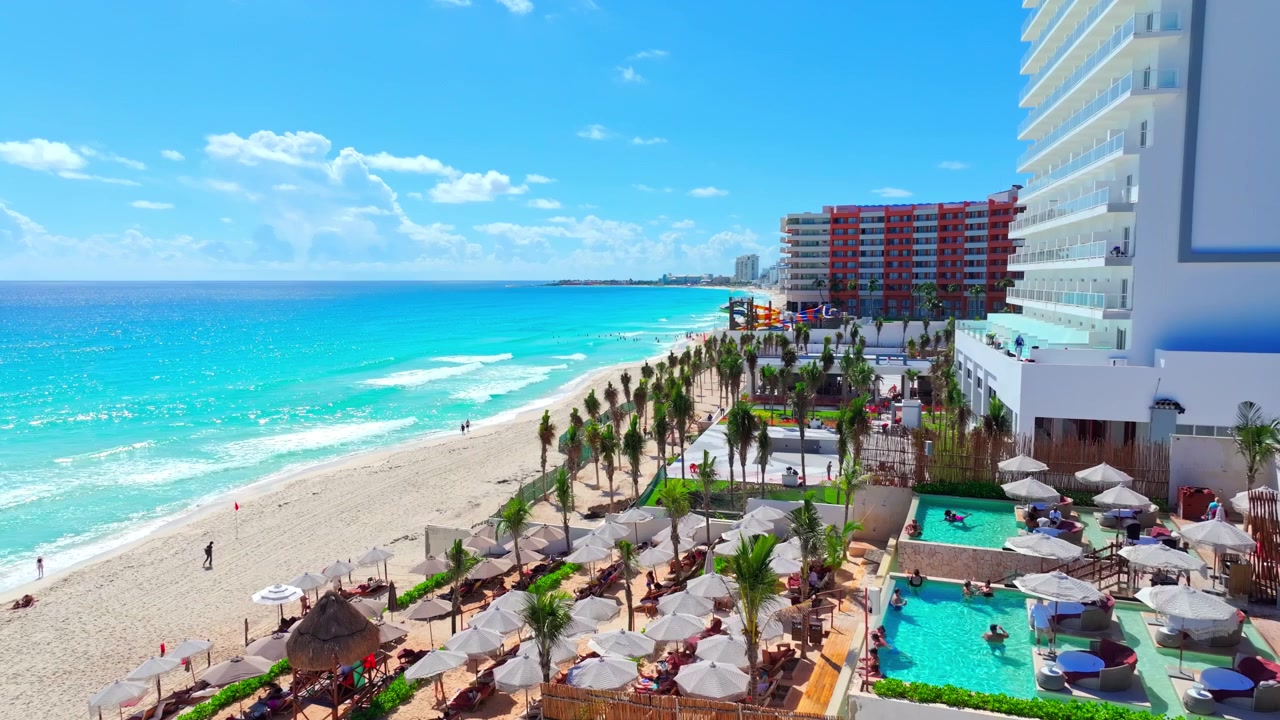 Vista aerea di un resort fronte mare con tetti rossi e piscine lungo la costa turchese della Zona Hotelera di Cancun, Quintana Roo, Messico.