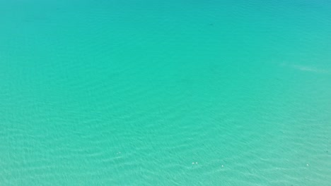 A-sweeping-view-of-the-crystal-clear-waters-and-white-sand-beaches-of-Playa-Balandra,-Mexico,-with-a-yacht-in-the-distance