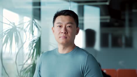 portrait of young asian man freelancer office worker teacher in modern room in casual clothes looking at camera. confident serious proud male indoors