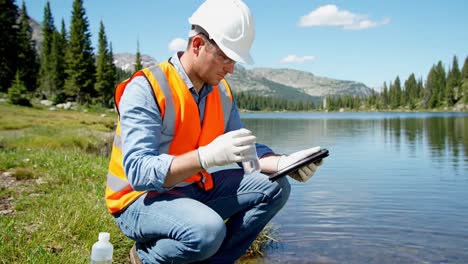 environmental scientist taking a water sample from a mountain lake for research