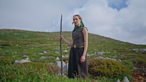 dreaming woman standing hill on outdoor journey. fashion model posing with stick