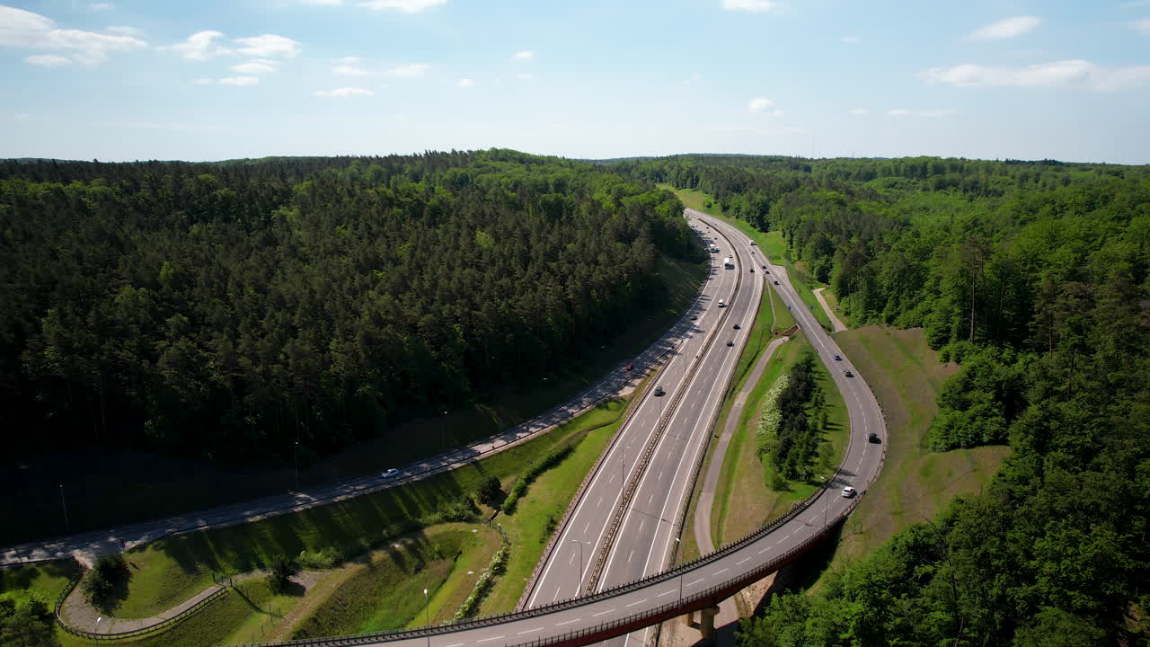 여름에 숲에 둘러싸인 새로운 아스팔트 도로에서 운전하는 자동차의 상승 항공 사진 - 4k 드론 파노라마