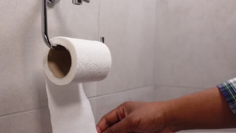 a person's hand reaches for toilet paper