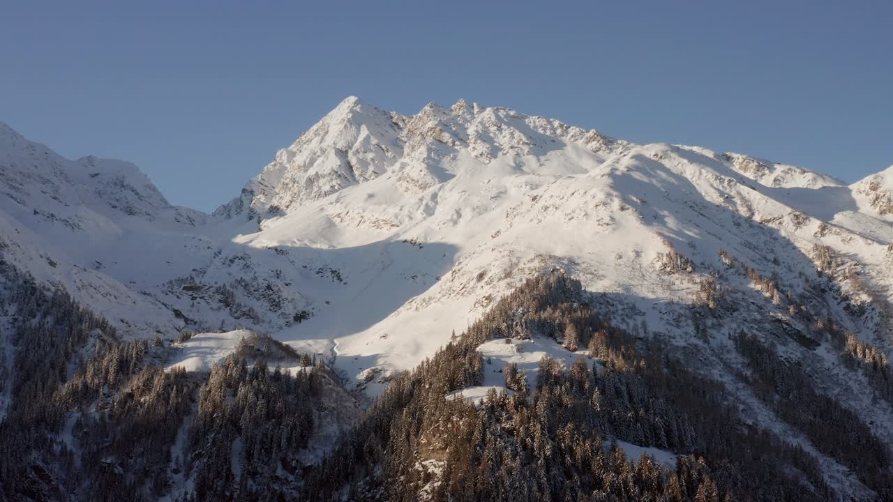 Slow aerial show going towards a snow covered mountain in the Alps