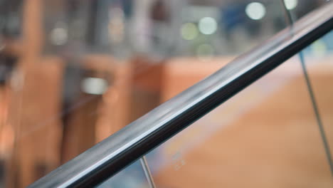 close-up of moving escalator handrail with blurred background showcasing motion in modern shopping mall, focus on smooth metallic surface reflecting light