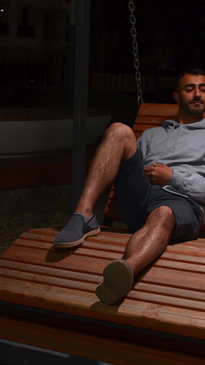 Homem relaxando em um banco de parque à noite