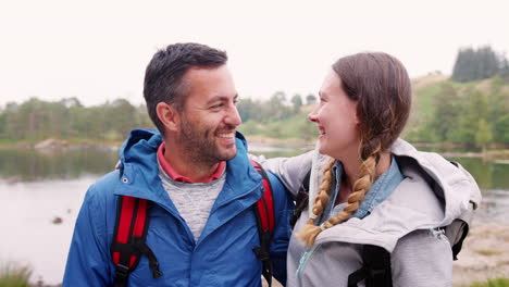 young adult couple standing on a camping trip standing near a lake looking at camera, close up, lake district, uk