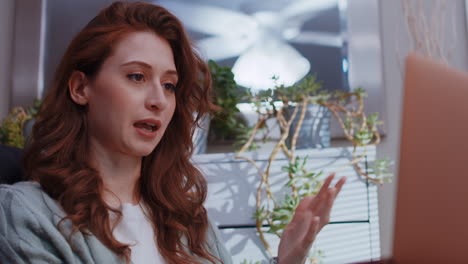 a young caucasian woman is working from home on her laptop, talking on a video call
