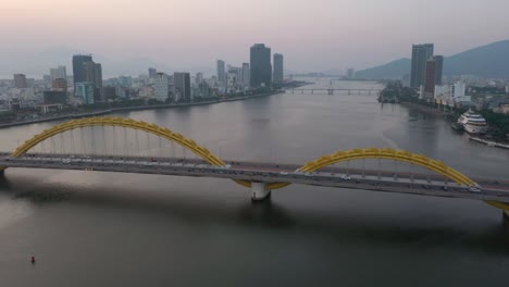 drone flying around dragon bridge cau rong, traffic and city skyline during sunset in danang, vietnam