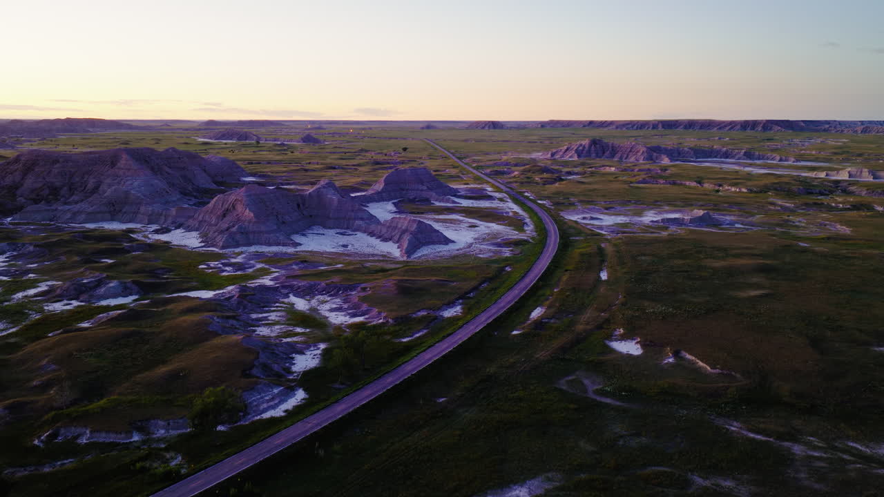 Sunset Aerial Views of Scenic Road Cutting Across Rugged Badlands