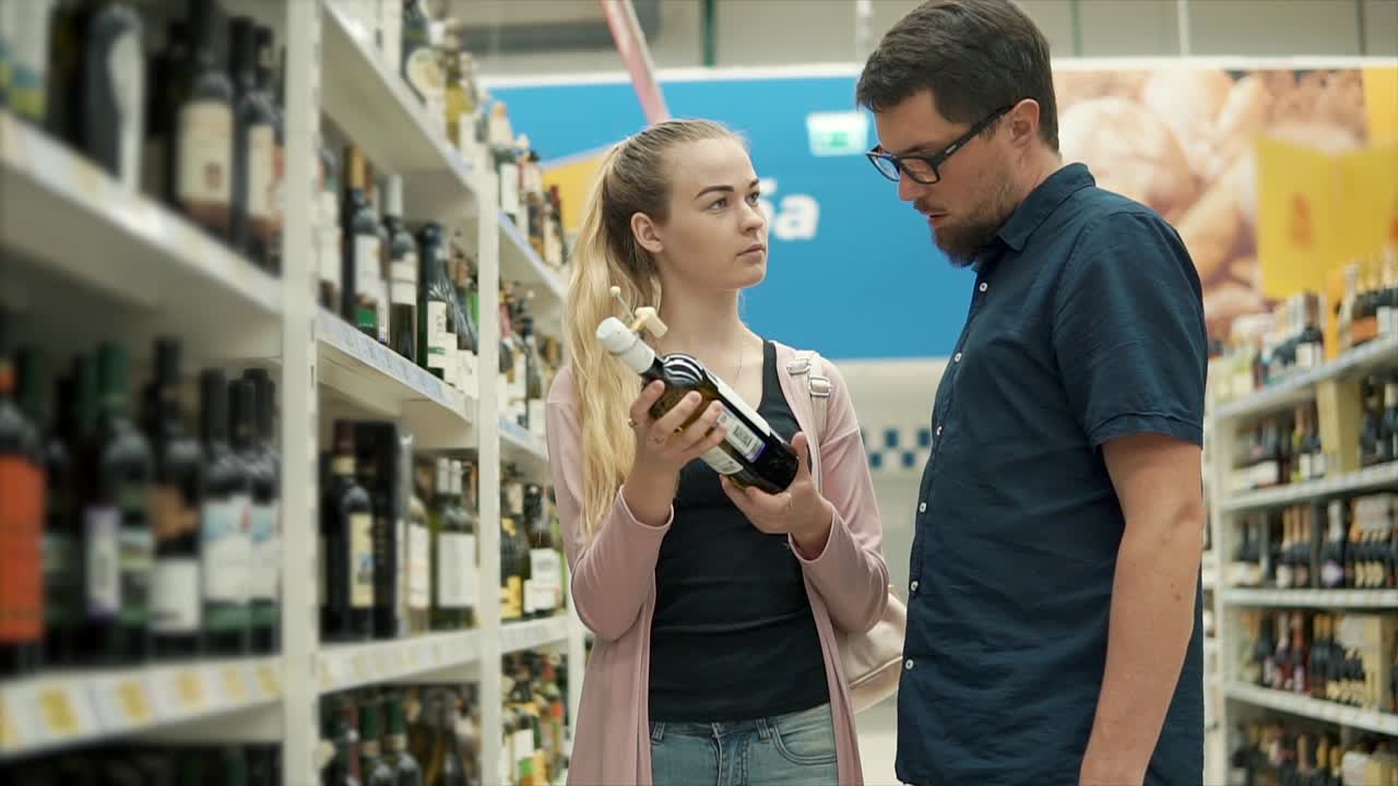 Casal escolhendo vinho num supermercado