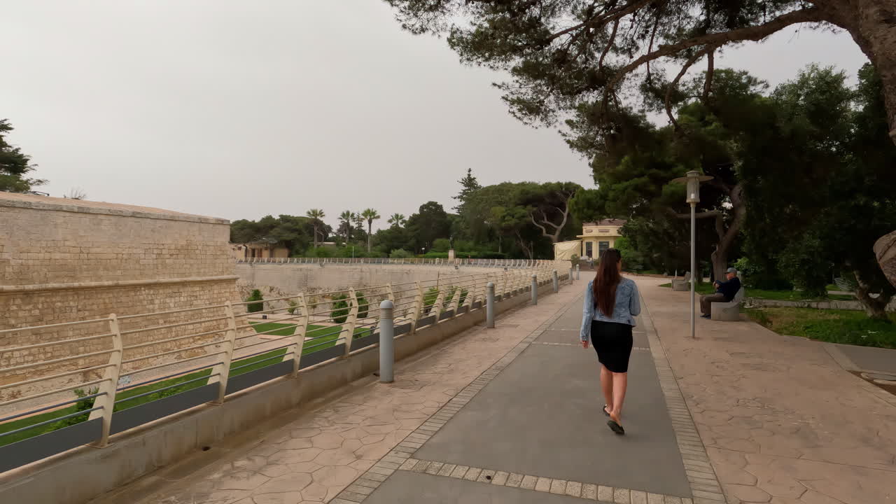 fotografía de una turista caminando por mdina, la antigua capital del estado de malta con edificios antiguos durante la noche