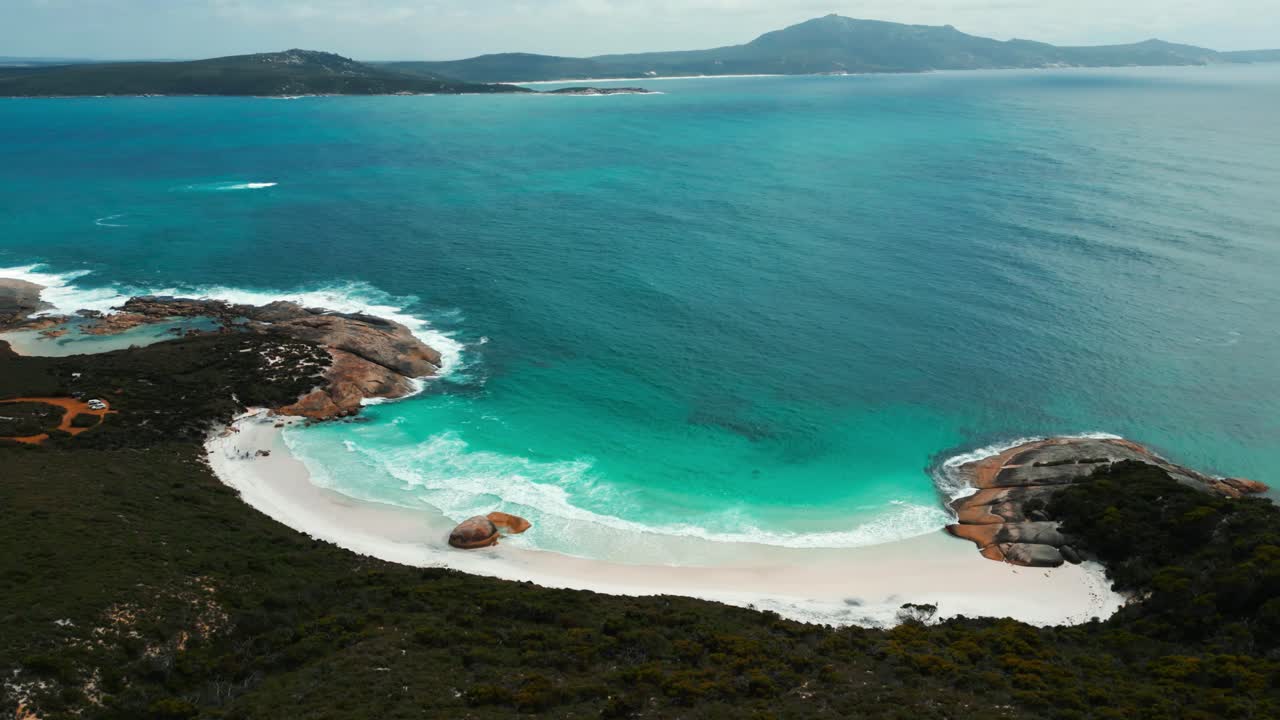 Vista panoramica su una piccola spiaggia a Two People Bay, vicino alla città di Albany nell'Australia Occidentale, in una giornata nuvolosa con acqua turchese e onde che si infrangono sulla spiaggia