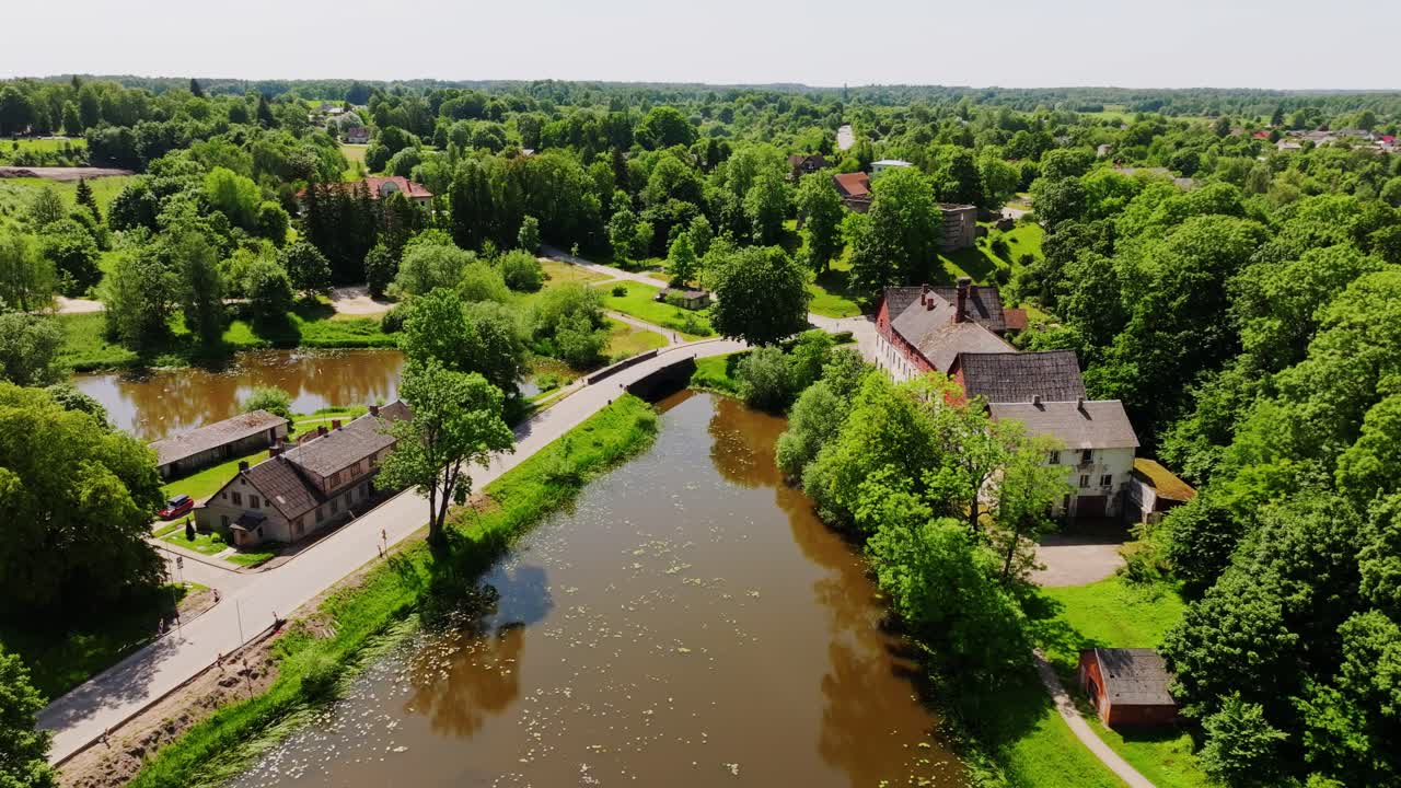 Cinematic Aerial Over Aizpute River and Old Town in Lush Summer Greenery