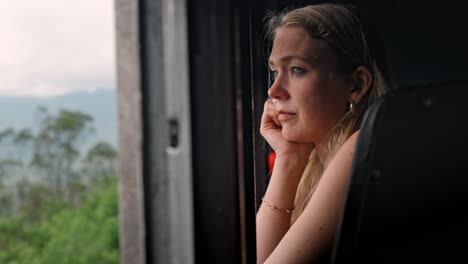 a woman gazes thoughtfully through the window of a moving train traveling the scenic ella to kandy route in sri lanka.