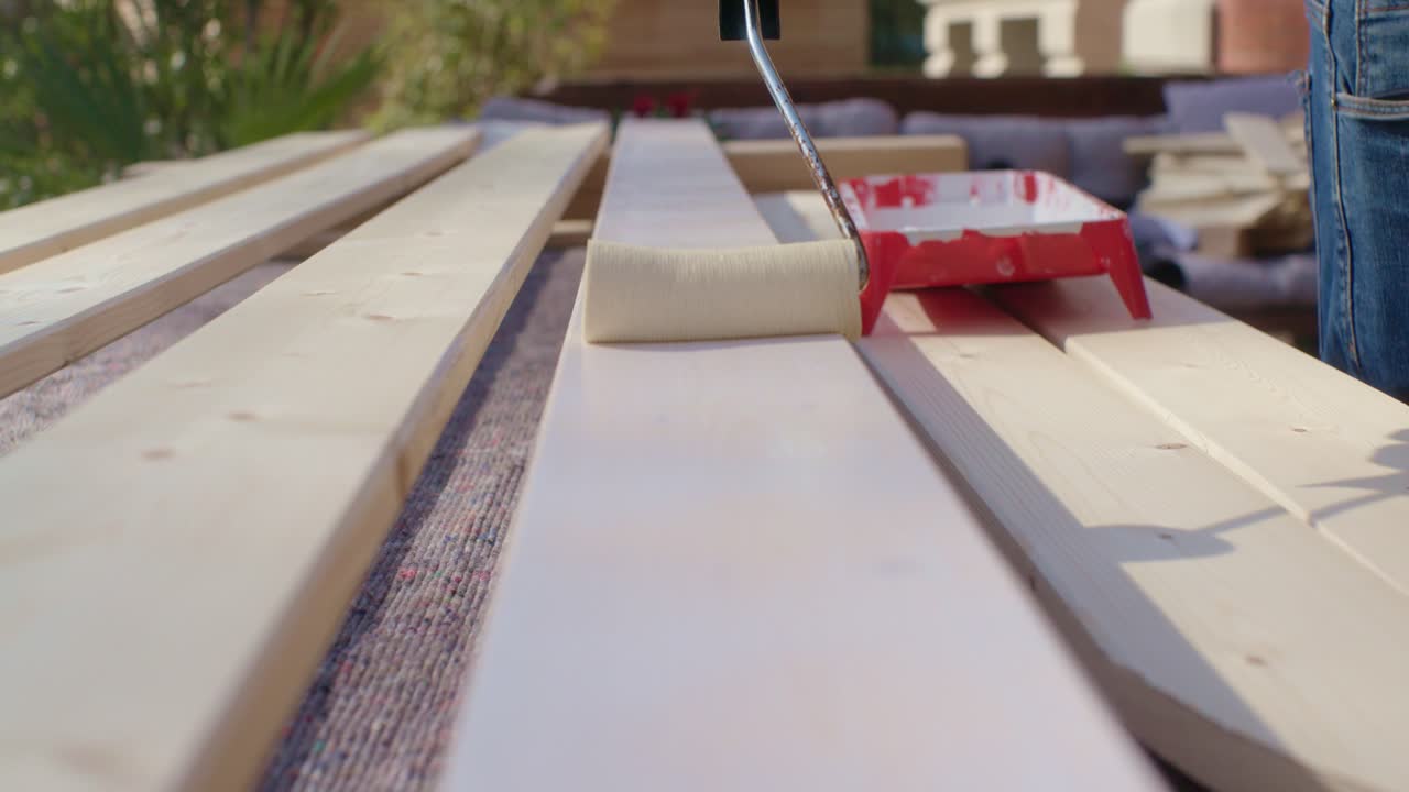 el artesano está pintando la madera con el rodillo de pintura