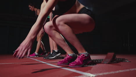 corredoras en la pista de atletismo agachadas en los bloques de salida antes de una carrera. en cámara lenta.