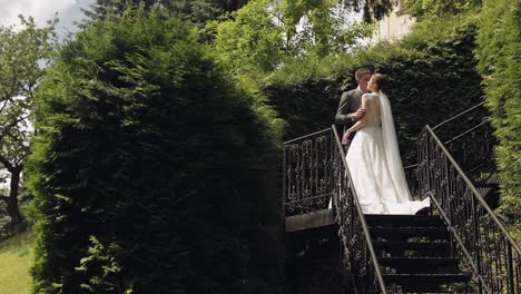 recién casados, novio caucásico con la novia quedarse en las escaleras en el parque, pareja de bodas, hombre y mujer enamorados