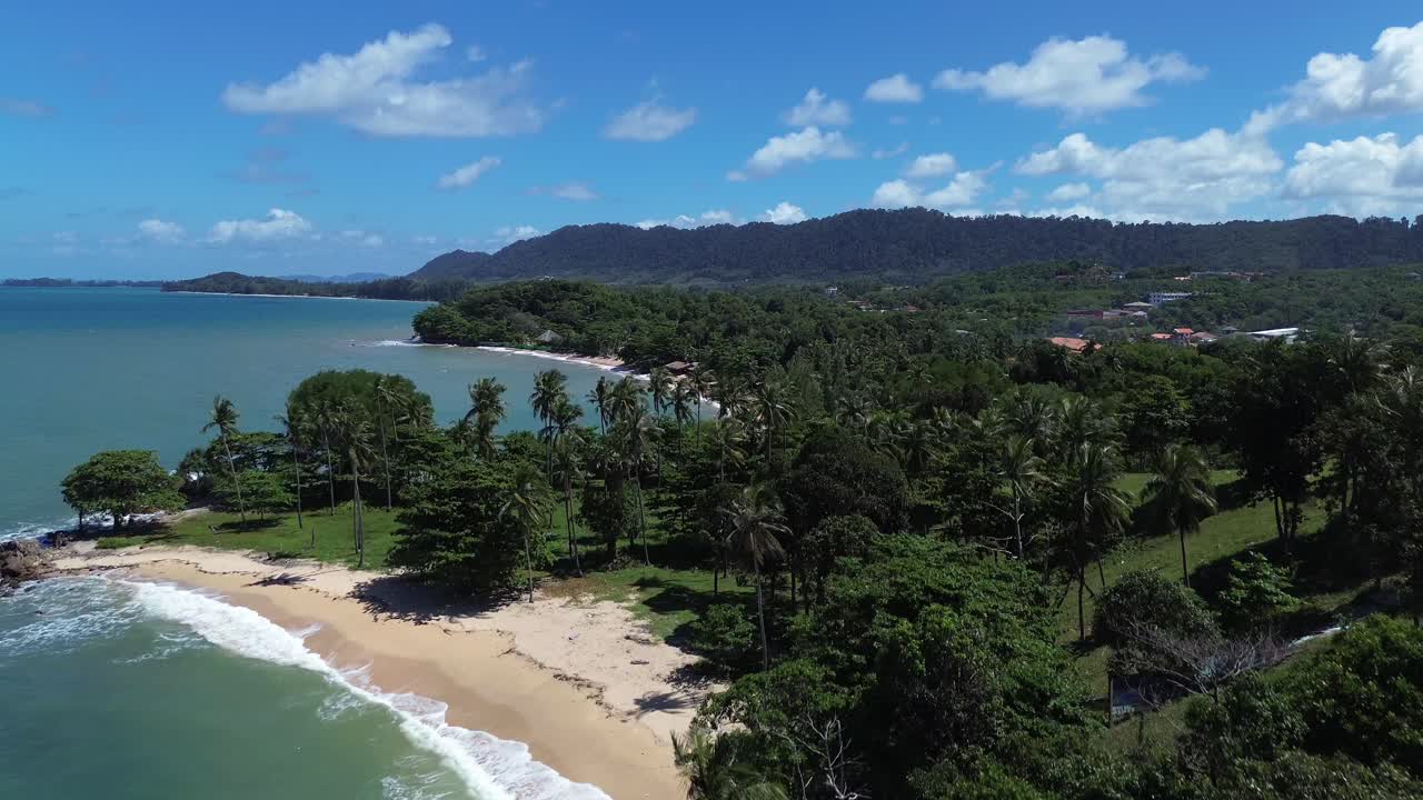 Cinematic drone shot rise above lush tropical forest on Koh Lanta, Thailand. Revealing a remote paradise beach with turquoise ocean water, white sand, and untouched coastal wilderness with no people