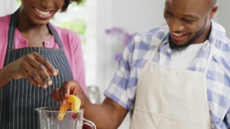 happy man and woman preparing juice in juicer
