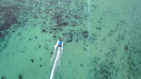 Drone-Persiguiendo-Un-Bote-De-Cola-Larga-En-Un-Agua-Turquesa-Y-Un-Mar-Cristalino,-Vista-De-4k-Desde-Arriba,-Impresionante-Toma-Aérea-De-Las-Islas-Phi-Phi,-Tailandia,-Rodeada-De-Agua