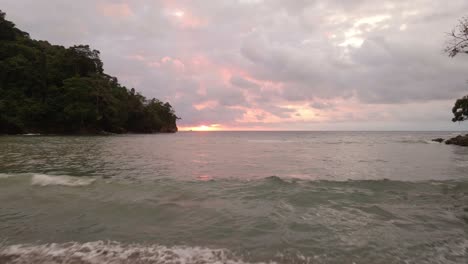 Hombre-Mirando-Hacia-El-Océano-En-Playa-La-Vaca-En-Costa-Rica-Volando-Su-Dron-Hacia-La-Puesta-De-Sol