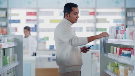 pharmacy drugstore: portrait of a handsome young indian man using smartphone device, chooses to purchase best medicine, drugs, vitamins. shelves full of sport supplements, health care products