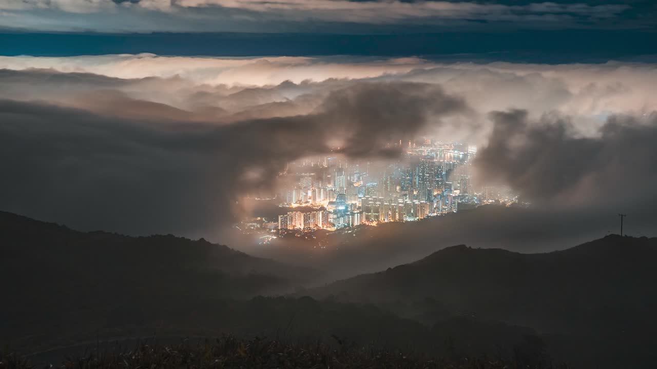 Surreal Night Time Lapse zoom over Tai Mo Shan, Hong Kong city with clouds moving. Beautiful night city lights of Tai Mo Shan ,cityscapes at mountain. Time lapse clouds on the top of mountain.