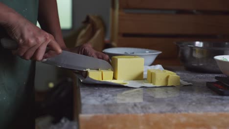 hard stick of butter being cut to smaller cubes, filmed as medium close up slow motion shot