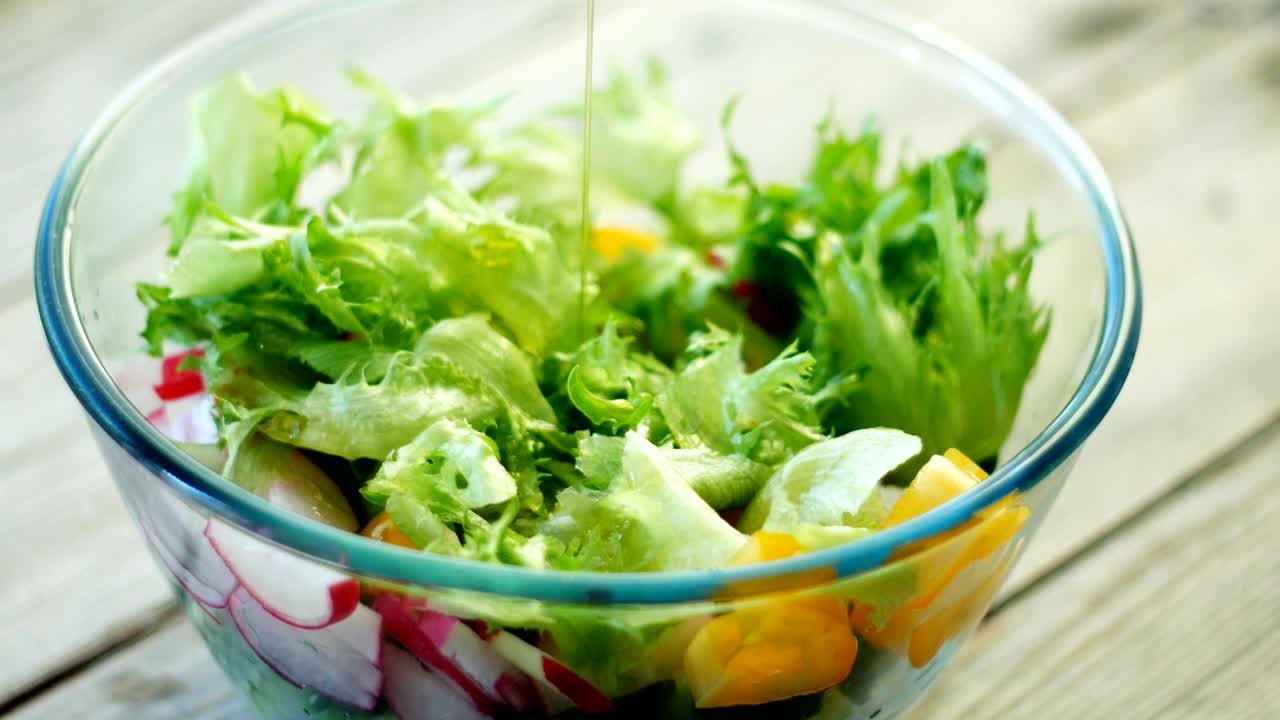 Closeup - pouring dressing over salad. Seamless cinemagraph looped video