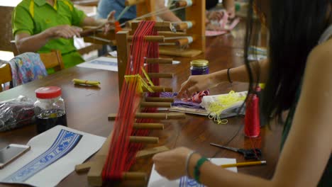 Gente-En-La-Mesa-Usando-La-Fabricación-Tradicional-De-Telares-Asiáticos