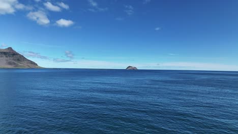 Fly-Over-The-Blue-Ocean-Towards-Skrudur-Island-In-Faskrudsfjordur,-East-Iceland