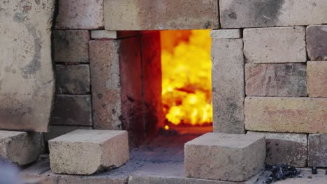 persona apilando ladrillos delante de la abertura de su horno para controlar el flujo de aire y el calor: conceptos de cerámica y horno