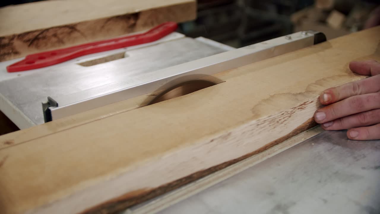 de cerca. el maestro corta una tabla de madera con una sierra circular en el taller de carpintería de un pequeño fabricante de muebles. cámara lenta.