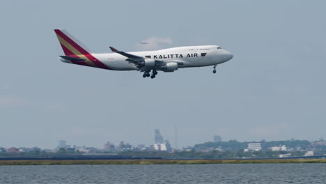 camera panning to follow kalitta airlines plane passing manhattan skyline to land at jfk airport