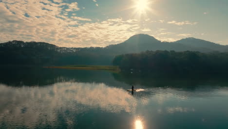 sunrise over a mountain lake with a kayaker