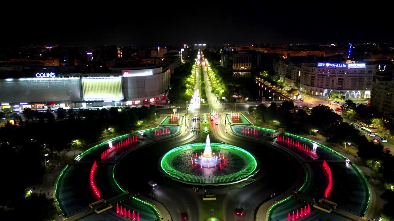 Bucharest city center at night. Drone passing forward above the famous Water Fountains. At lefti si Unirii Shopping Center. Night lifestyle. Travel destination. Aerial panoramic view