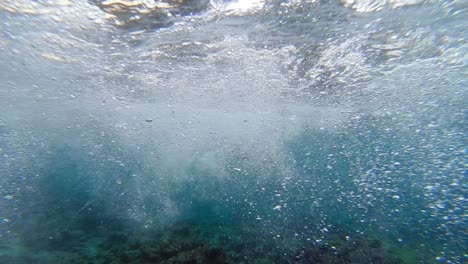 following-shot-of-caucasian-woman-snorkeling-in-clear-water-with-bubbles-surrounding-her