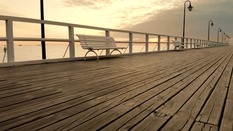 aerial footage boards and benches on the pier at sunrise at the seaside