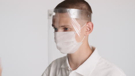 man wearing transparent protective mask over white face mask