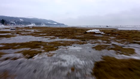 drone speeding over the frozen saint-lawrence river before moving up in charlevoix