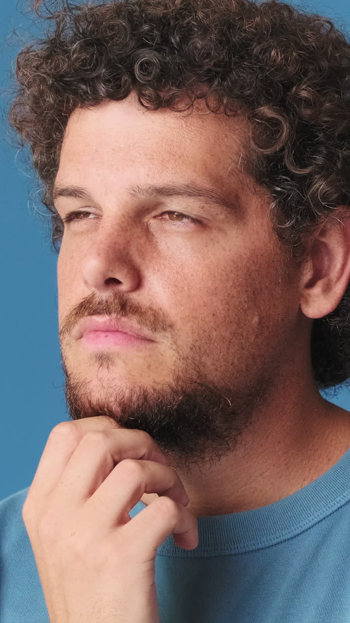 Primo piano di un uomo dai capelli ricci, assorto nei pensieri.