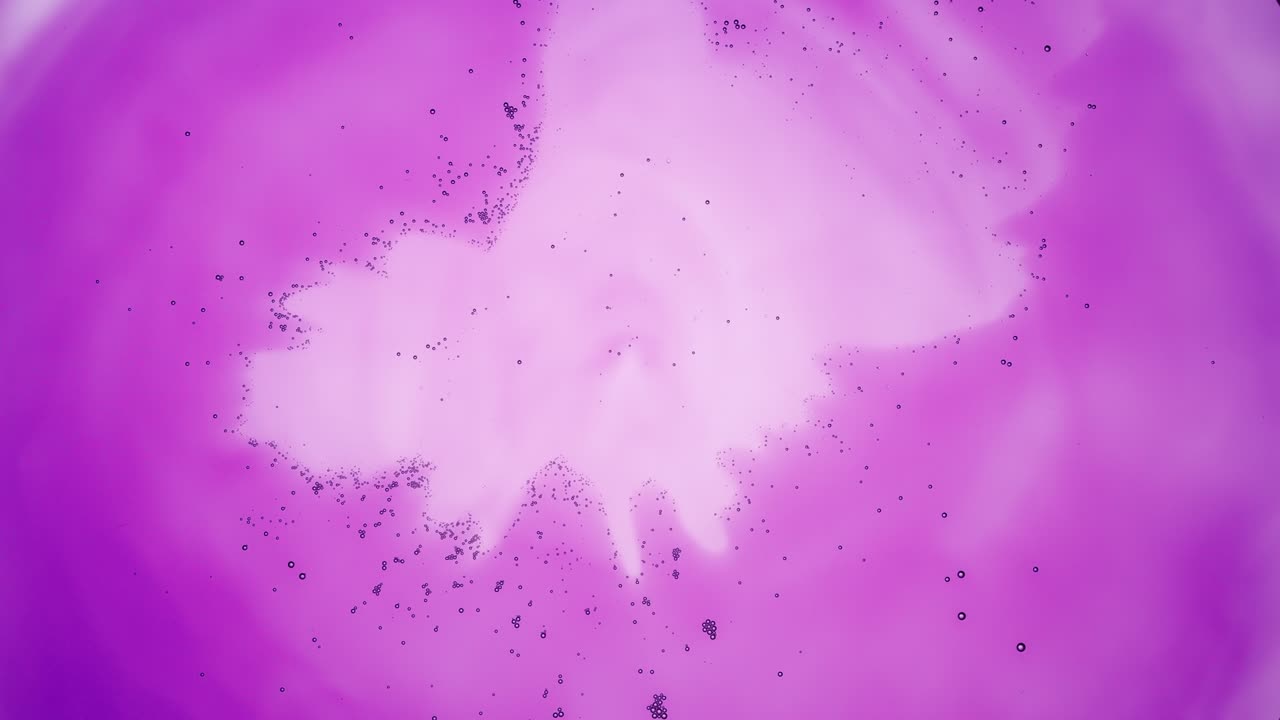 pequeñas burbujas claras grises se mueven hacia el centro del líquido púrpura