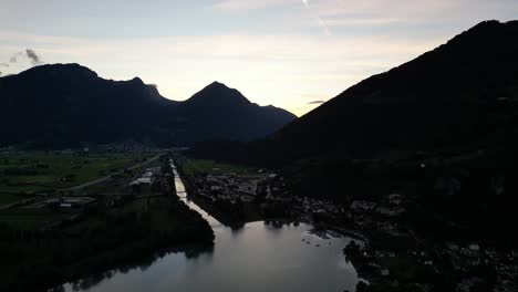 Stunning-drone-view-of-dark-mountains-with-green-meadow-over-Walensee-lake,-Switzerland-in-the-early-morning