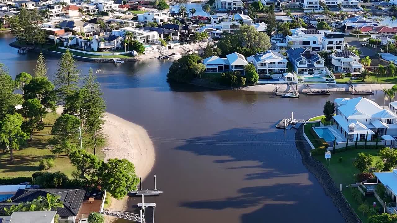 Vídeos stock de drone mostrando propriedades residenciais de luxo e docas particulares ao longo de um rio panorâmico