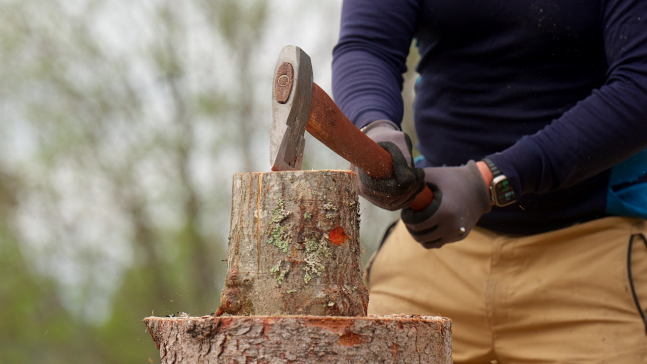 Man Splitting The Wooden Logs Using An Axe. - closeup shot