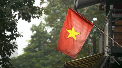 vietnamese flag in a wooden stick hanging outside in hanoi, vietnam - closeup shot