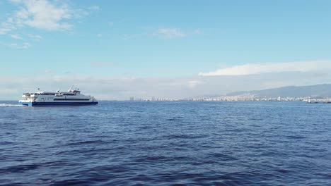 Vista-Diurna-De-Un-Barco-De-Pasajeros-Que-Sale-Del-Puerto-De-Alsancak-En-Izmir,-Con-El-Mar-Azul-Profundo-Visto-Desde-El-Cordón-De-Izmir