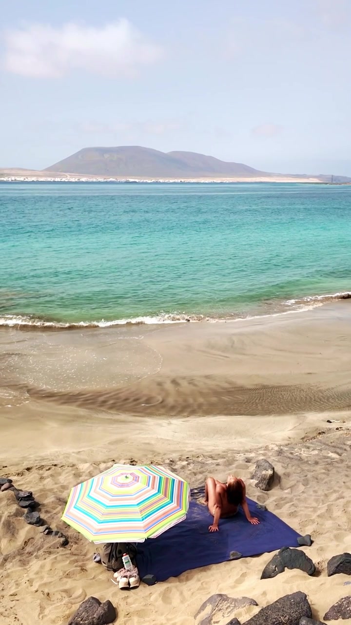 Donna solitaria che si rilassa sulla spiaggia di Risco a Lanzarote
