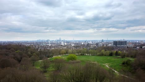 drone shot flying over hampstead heath park with london in backdrop